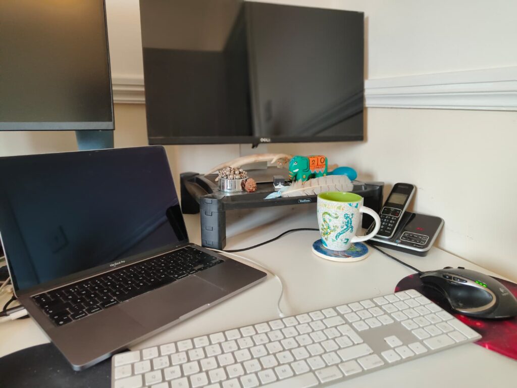 A picture of a desktop with tea, a monitor and a mac