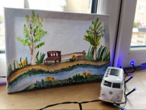 A painting on a canvas of a riverside scene with a bench